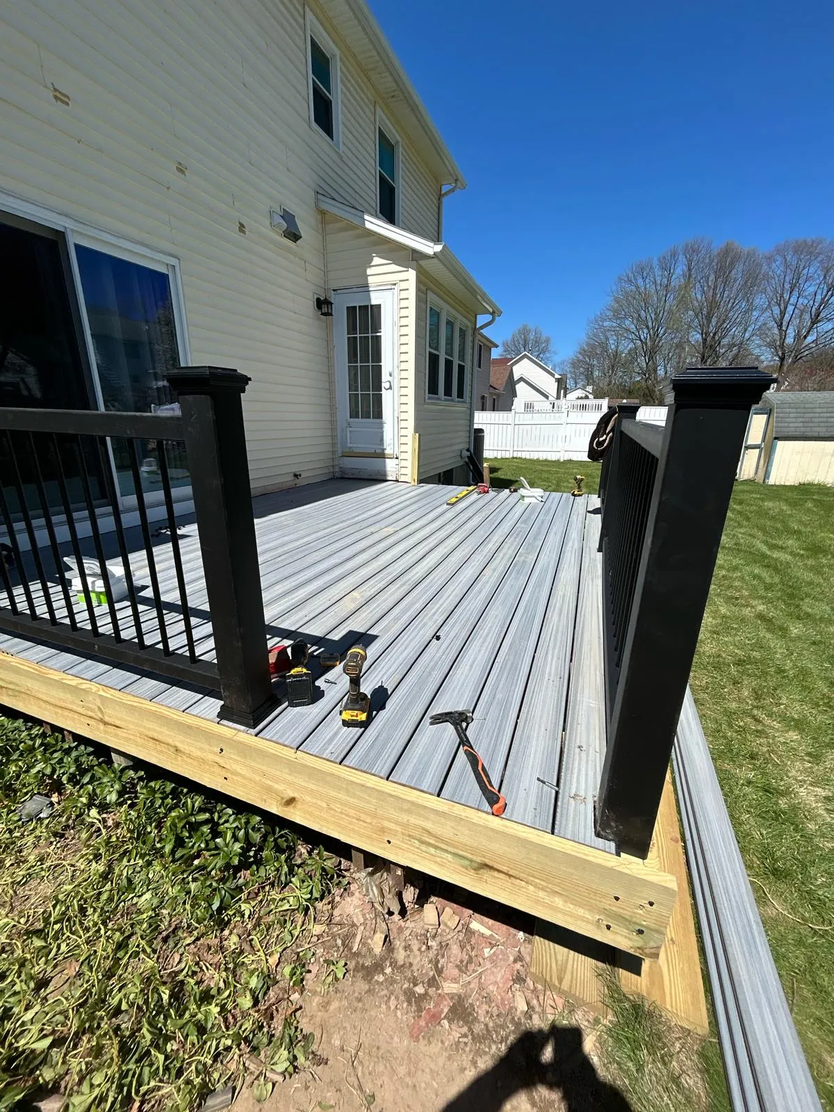 Ground-level gray composite deck with black railings beside an Indianapolis home