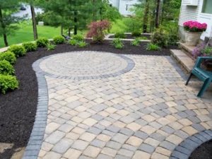 Paver patio with circular stone medallion and landscaped border in Indianapolis