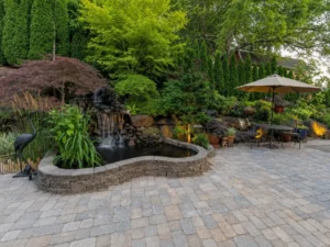 Paver patio with waterfall pond, stone border, and umbrella seating in Indianapolis