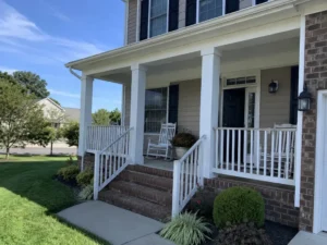 Covered front porch with white columns, white railings, and brick steps in Indianapolis