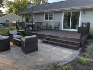 Ground-level gray composite deck with illuminated steps beside a paver patio in Indianapolis